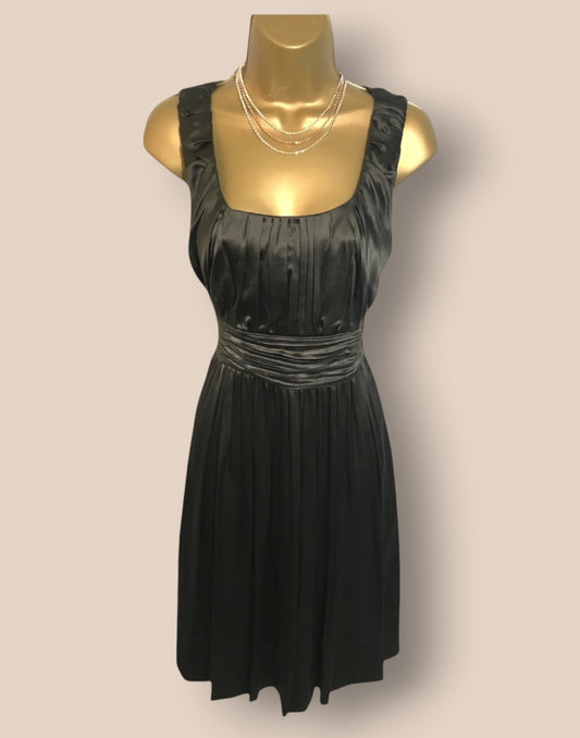 Black dress on a gold mannequin against a plain background