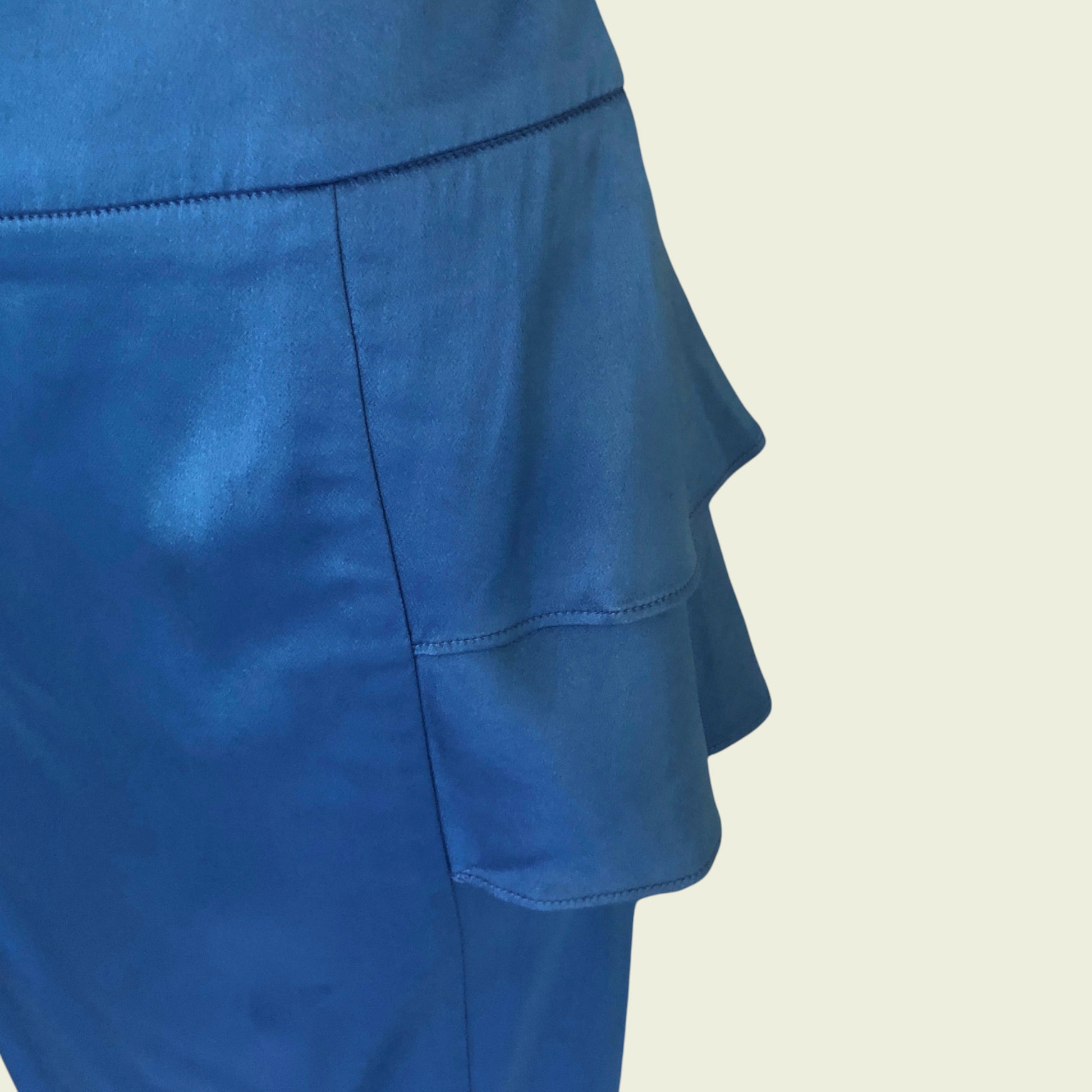 Blue skirt with ruffled layers on a beige background