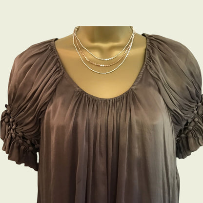 Brown dress with ruched sleeves on a mannequin against a beige background