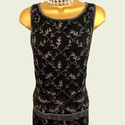 Black sleeveless top with silver leaf pattern on a mannequin against a beige background