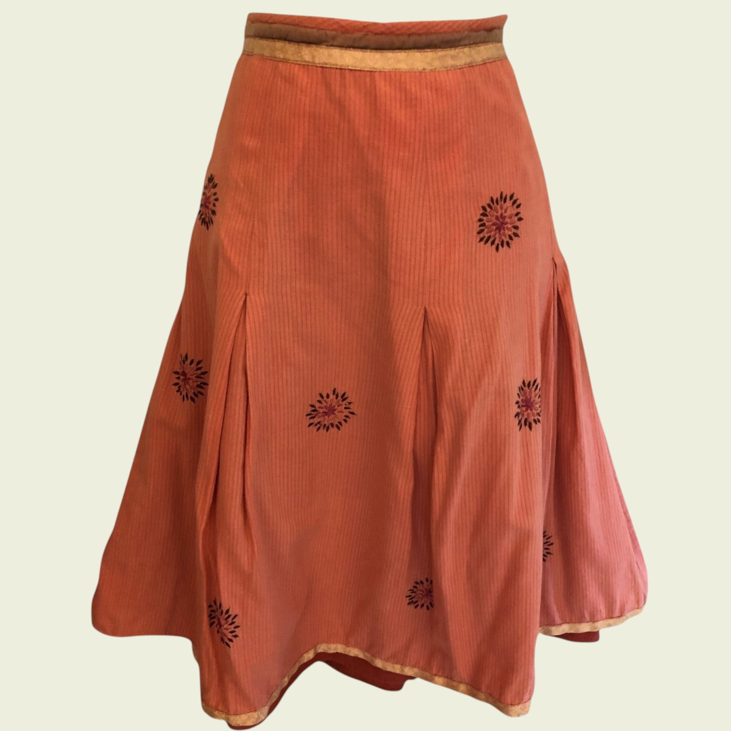 Orange skirt with black floral patterns on a beige background