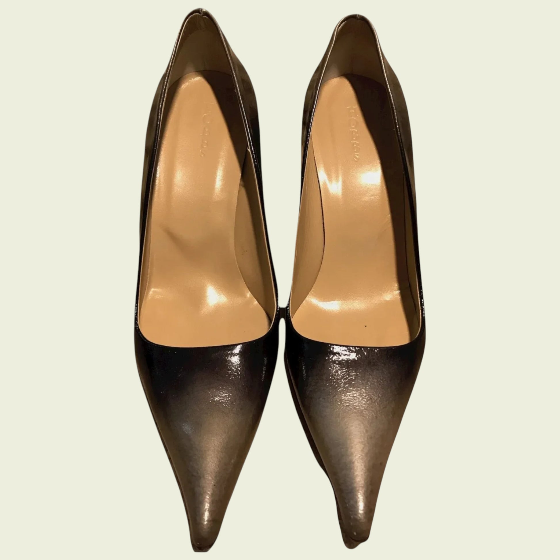 Pair of bronze high-heeled shoes on a light beige background