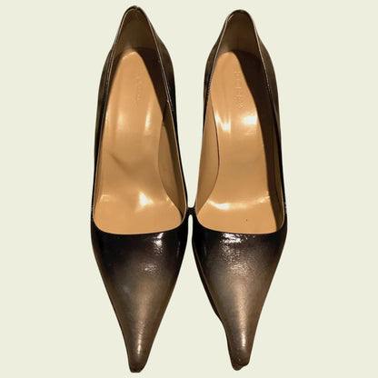 Pair of bronze high-heeled shoes on a light beige background