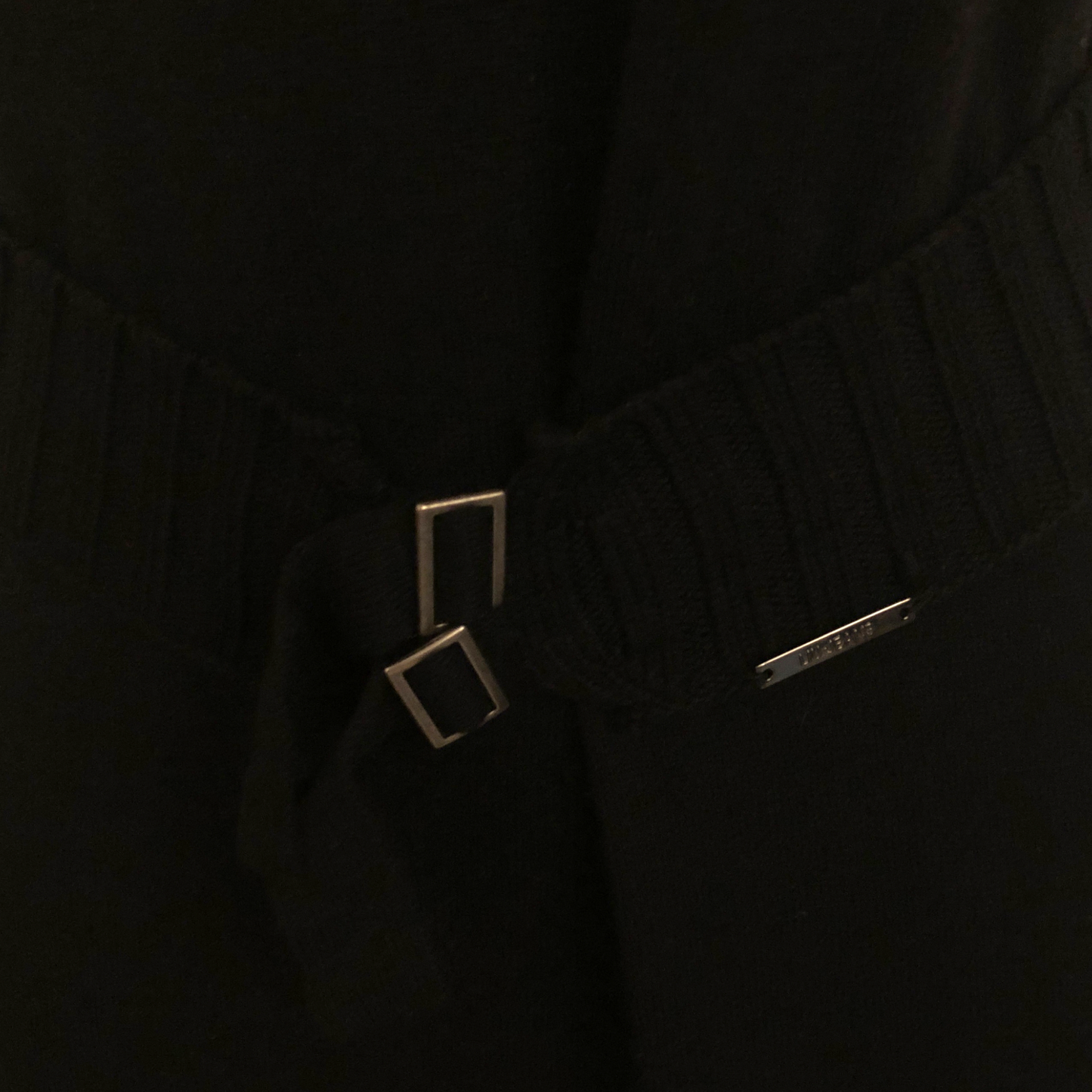 Close-up of a black garment with a belt and square buckle.