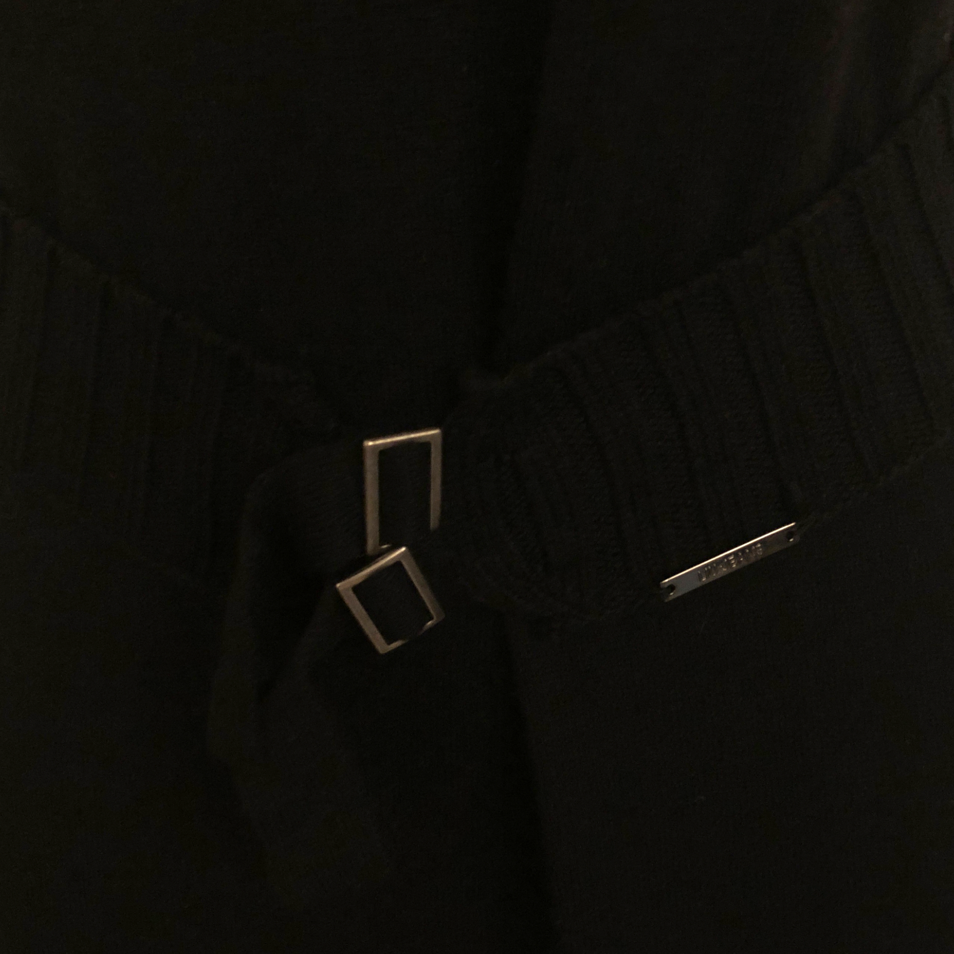 Close-up of a black garment with a belt and square buckle.