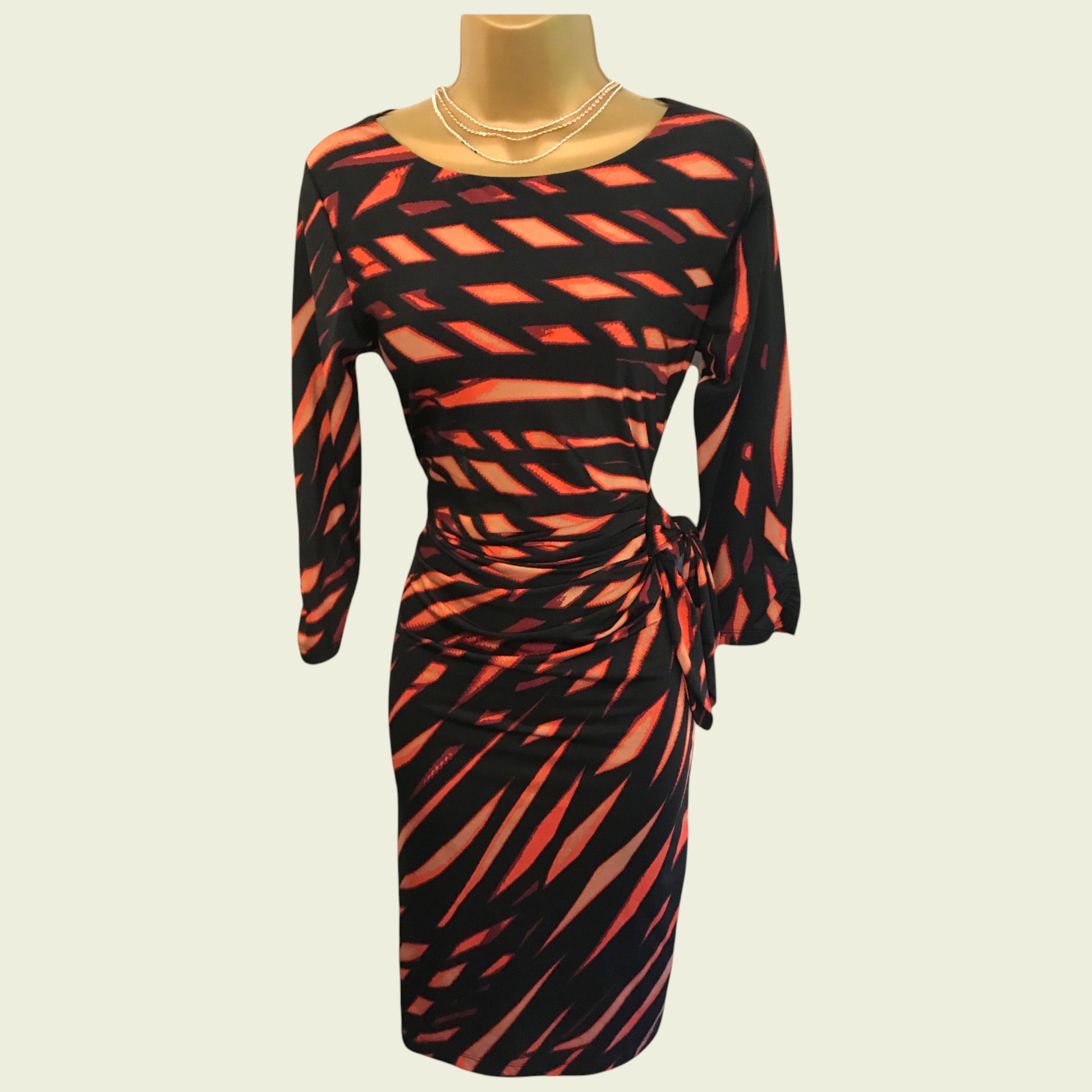 Black and orange patterned dress on a mannequin against a beige background