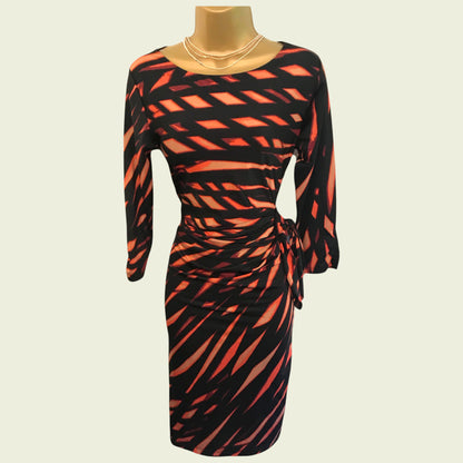 Black and orange patterned dress on a mannequin against a beige background