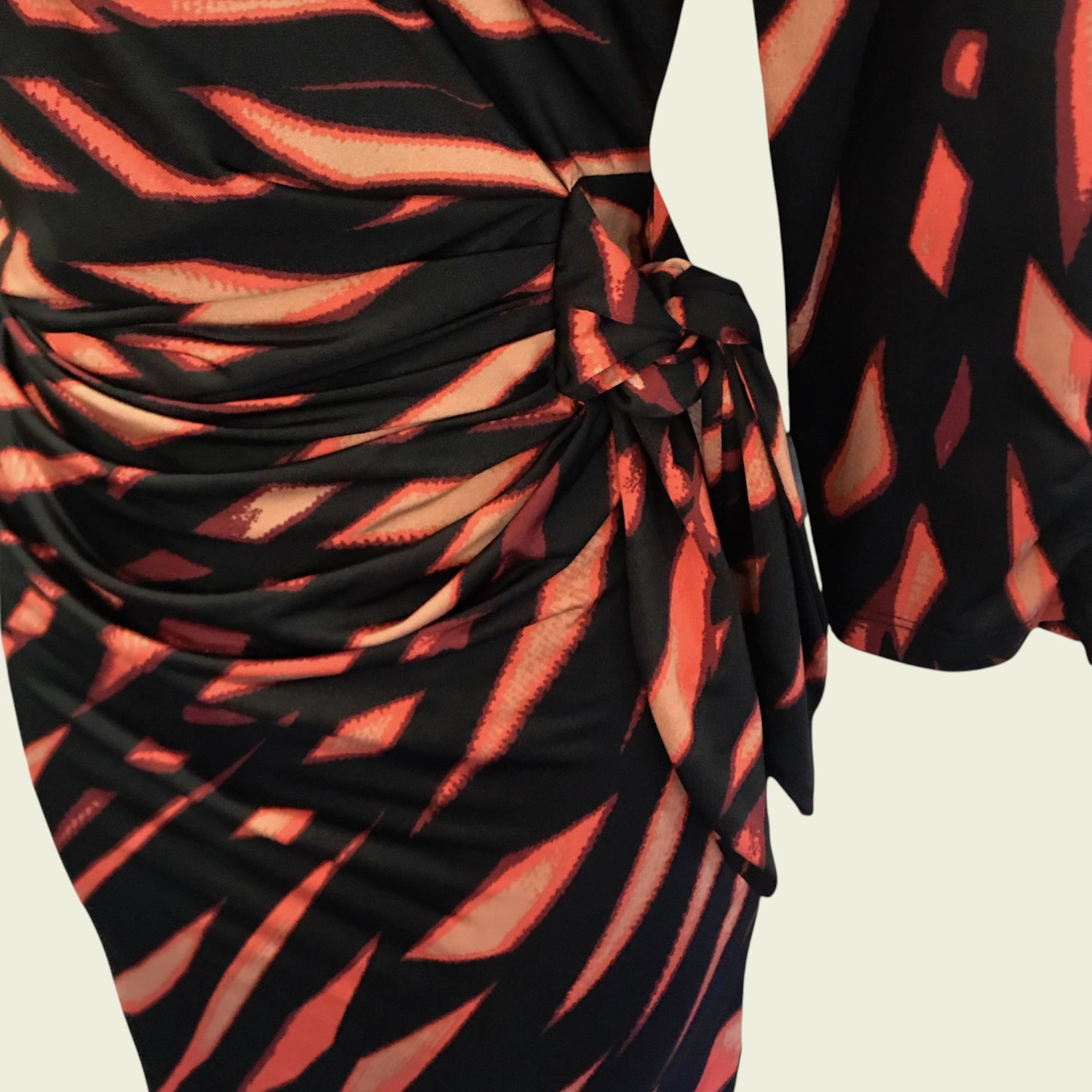 Black and orange patterned dress with a tie detail on a beige background