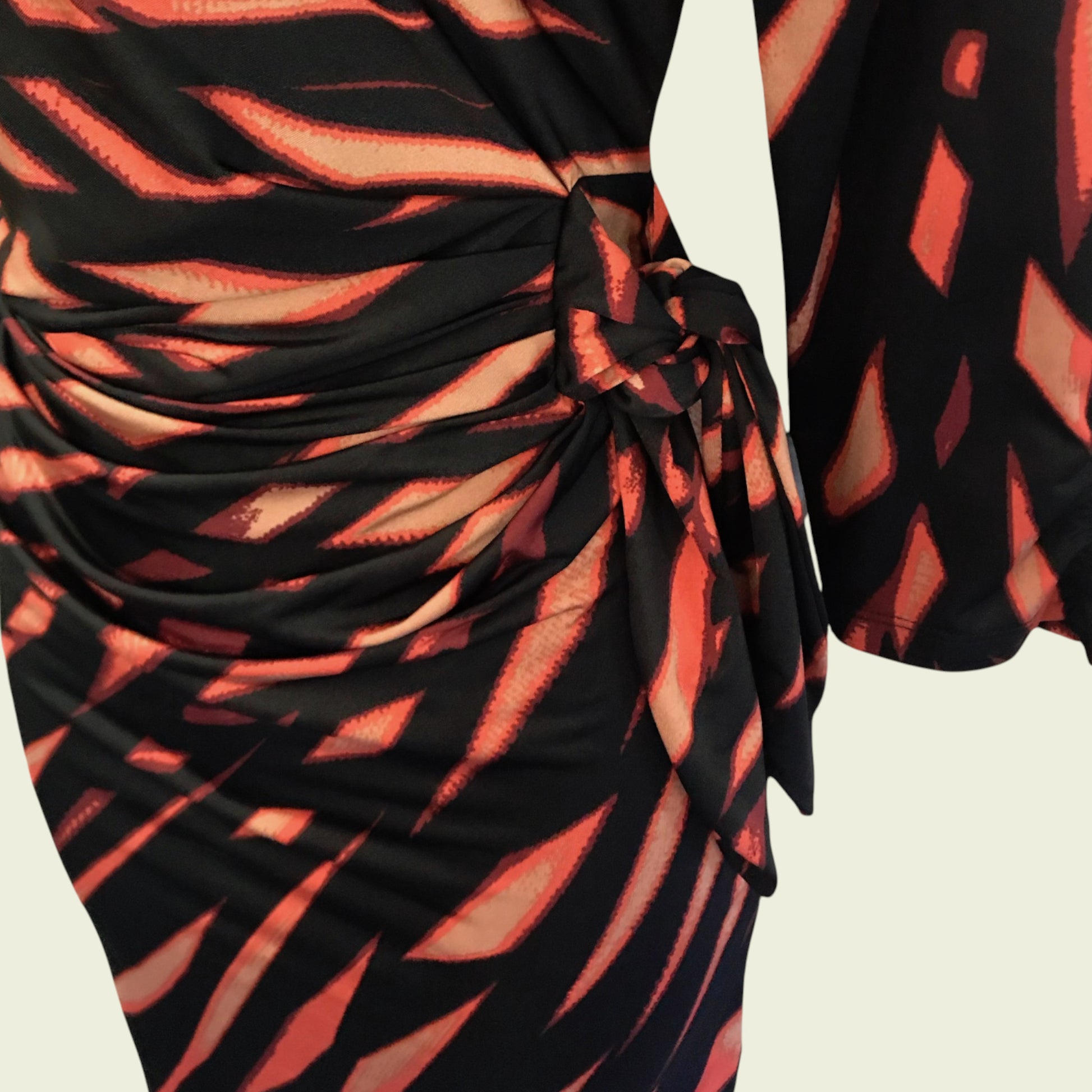 Black and orange patterned dress with a tie detail on a beige background