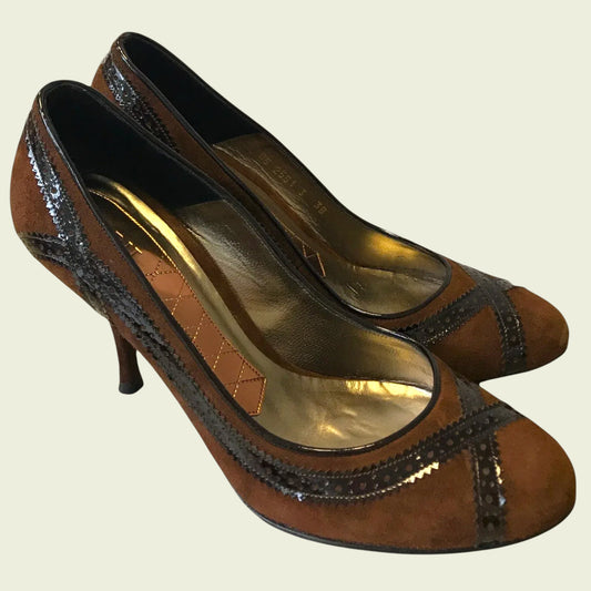 Pair of brown high-heeled shoes with black accents on a beige background