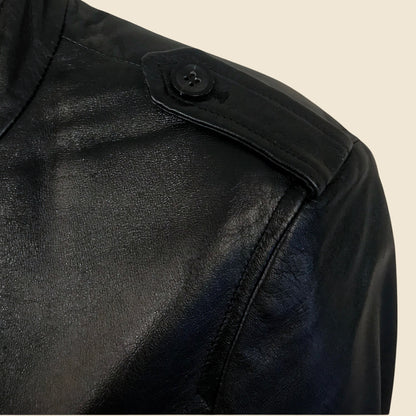 Close-up of a black leather jacket with a button on a beige background