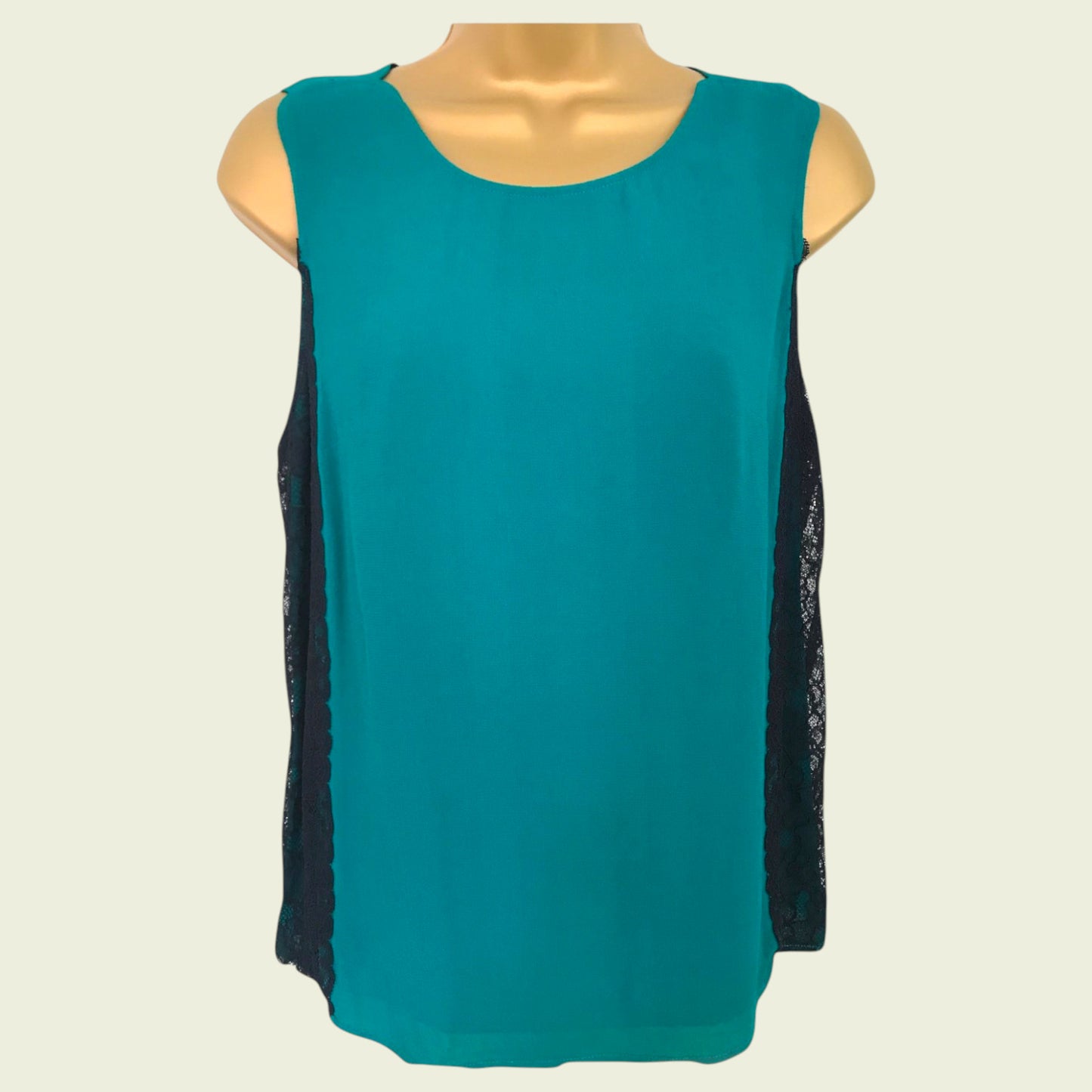 Teal sleeveless top with black lace sleeves on a mannequin against a beige background