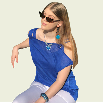 Woman wearing a blue top and sunglasses against a light background