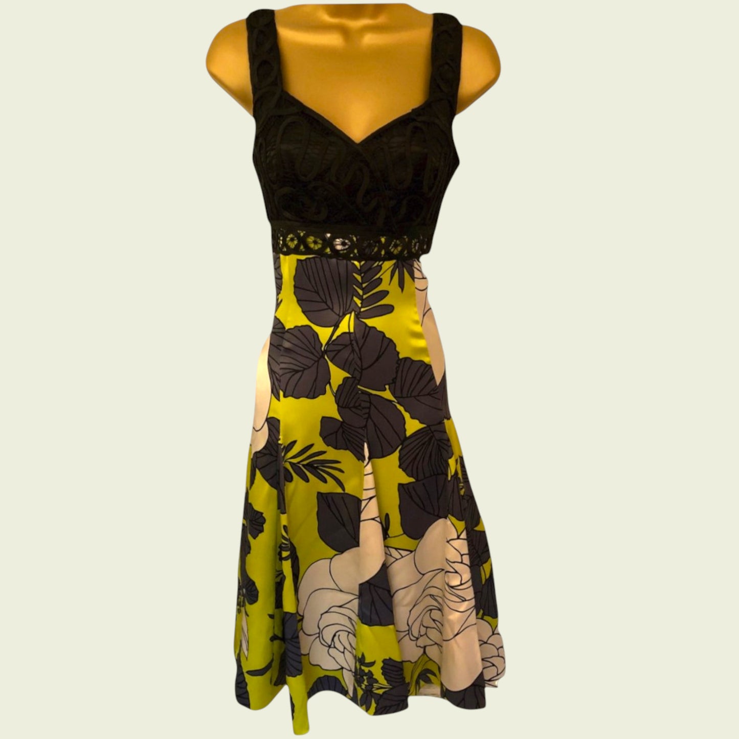 Mannequin wearing a black and yellow floral dress on a beige background