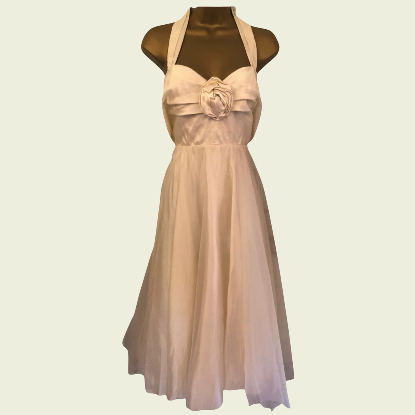 Mannequin wearing cream organza prom dress on beige background