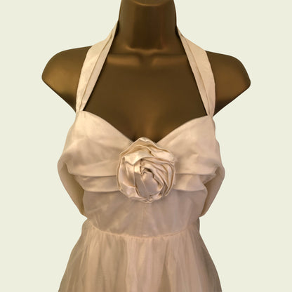 Mannequin wearing cream organza prom dress with rose detail on beige background