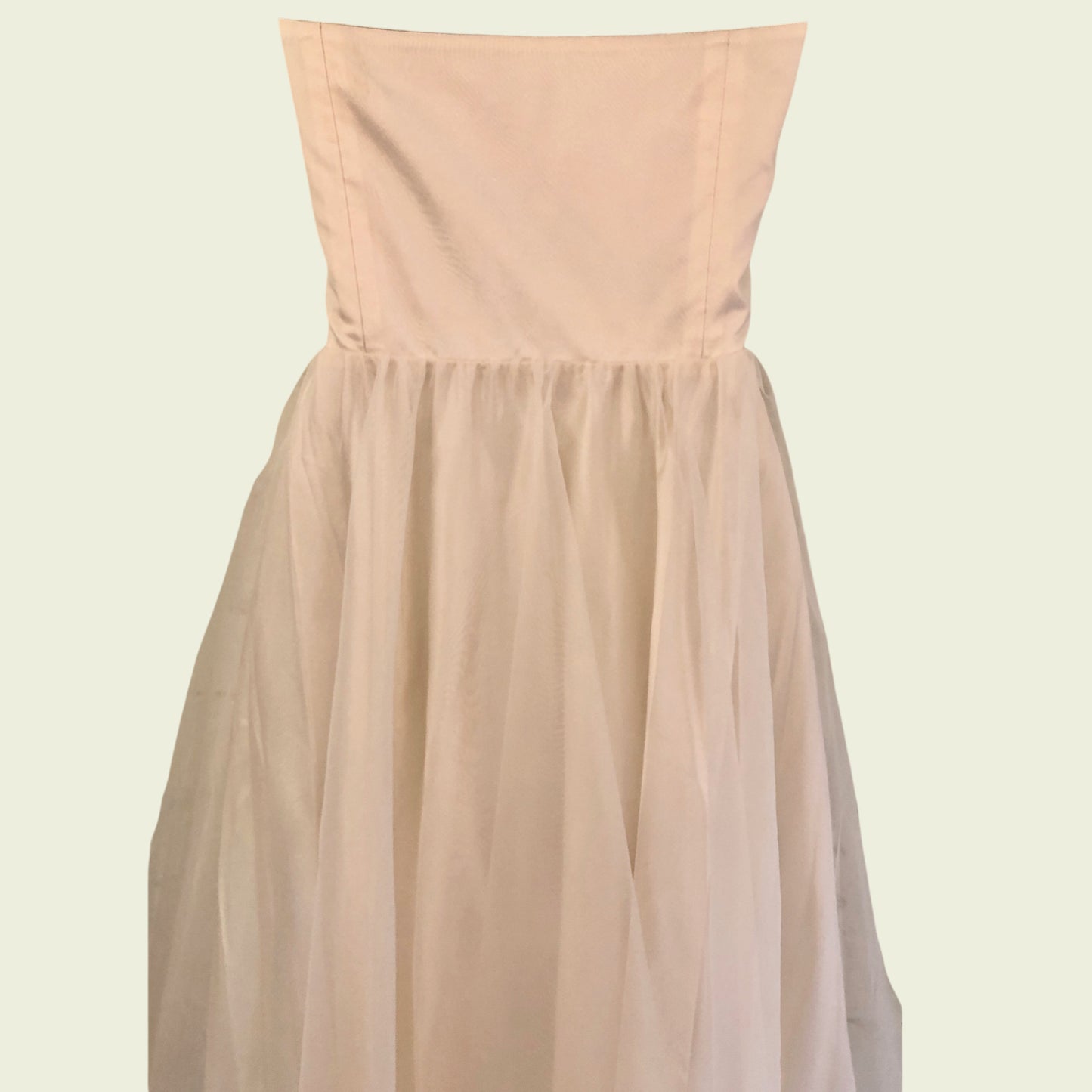 Mannequin wearing cream organza prom dress on beige background