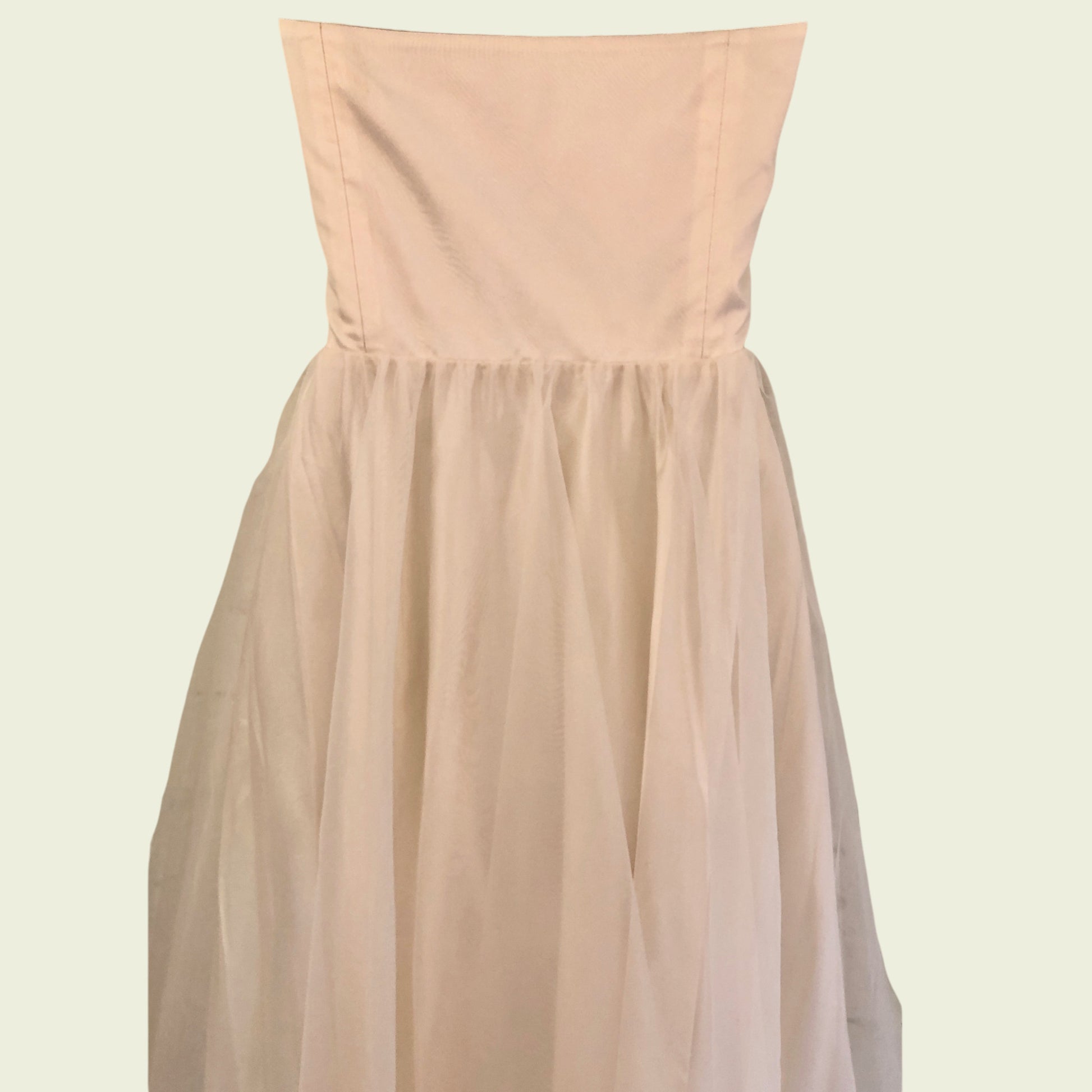 Mannequin wearing cream organza prom dress on beige background