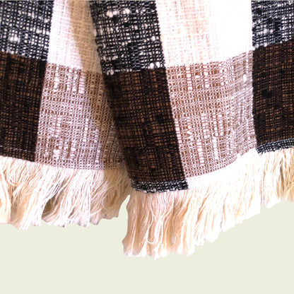 Close-up of a plaid fabric with fringes on a light green background