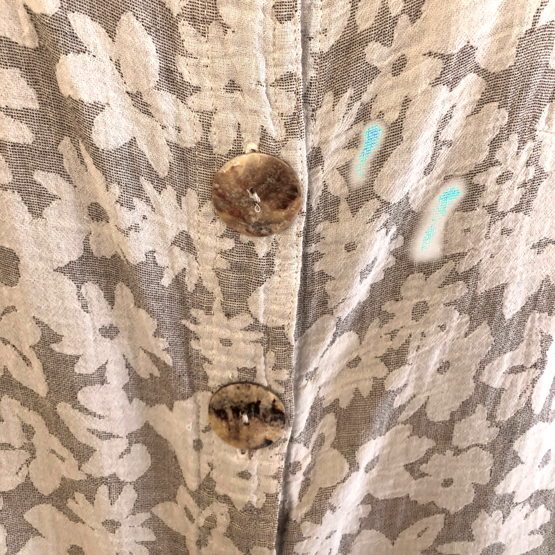 Close-up of a floral-patterned fabric with buttons on a textured background