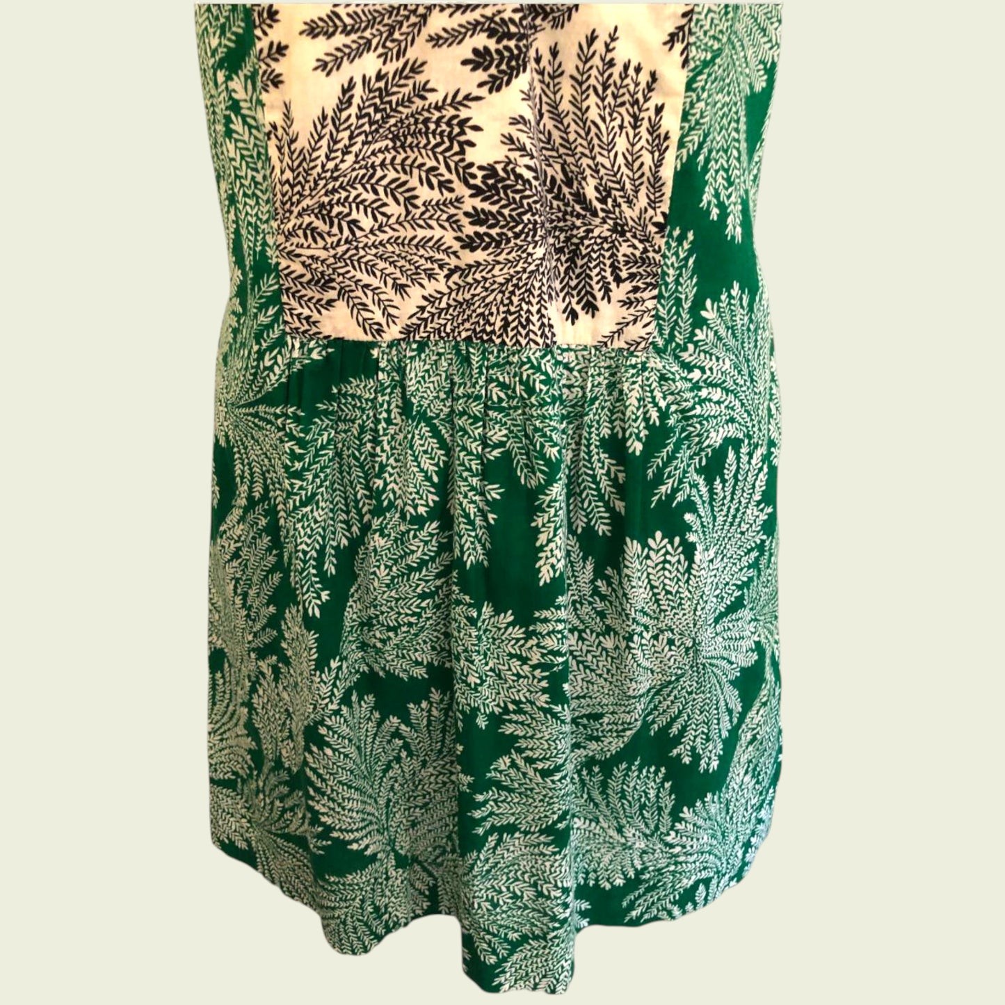 Green dress with fern leaf pattern on a beige background