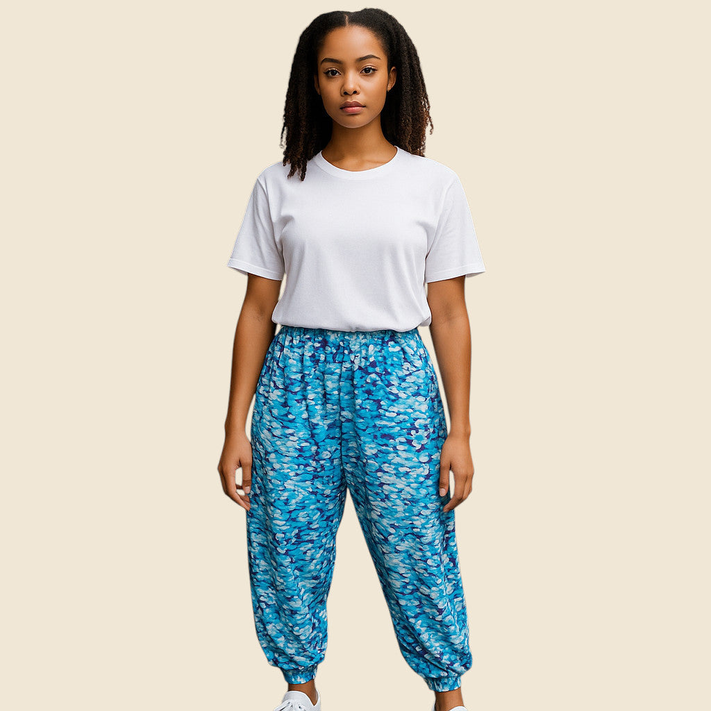 Person wearing a white t-shirt and blue patterned pants on a beige background