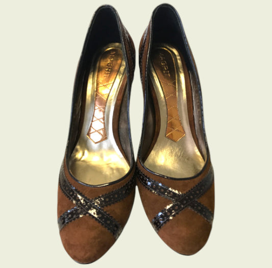 Pair of brown high-heeled shoes with decorative straps on a light beige background