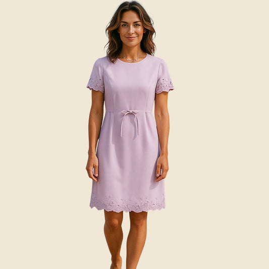 Woman wearing a light purple dress with lace details on a beige background