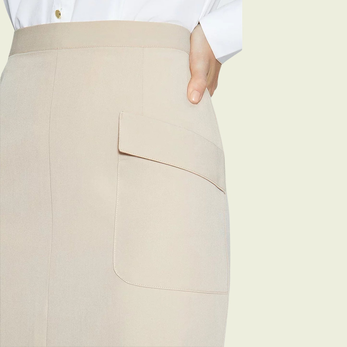 Model wearing a beige skirt showing pocket detail on a beige background