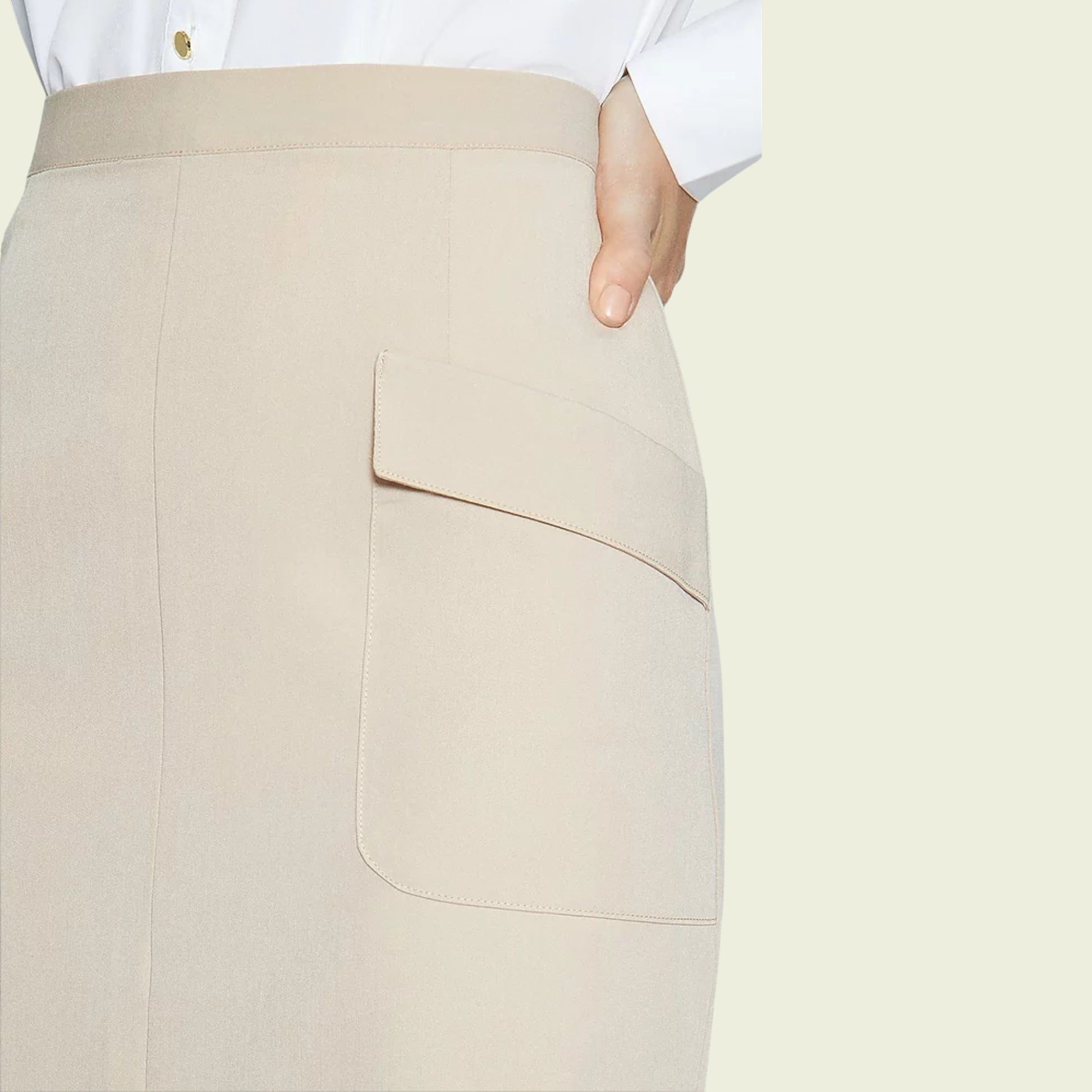 Model wearing a beige skirt showing pocket detail on a beige background