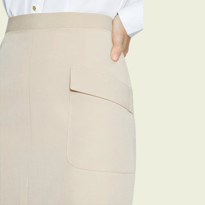 Model wearing a beige skirt showing pocket detail on a beige background
