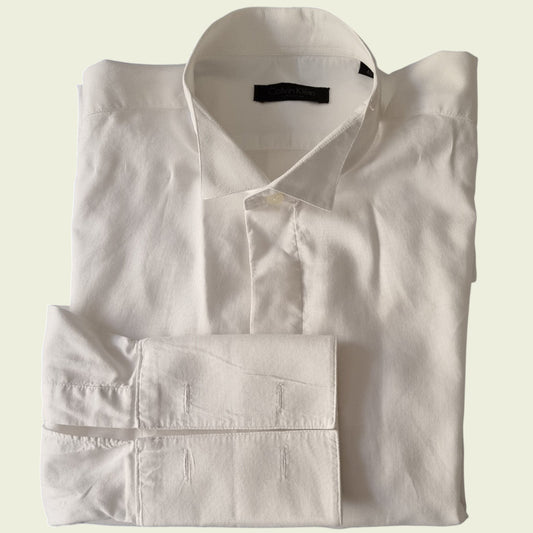 Folded white dress shirt on a light beige background