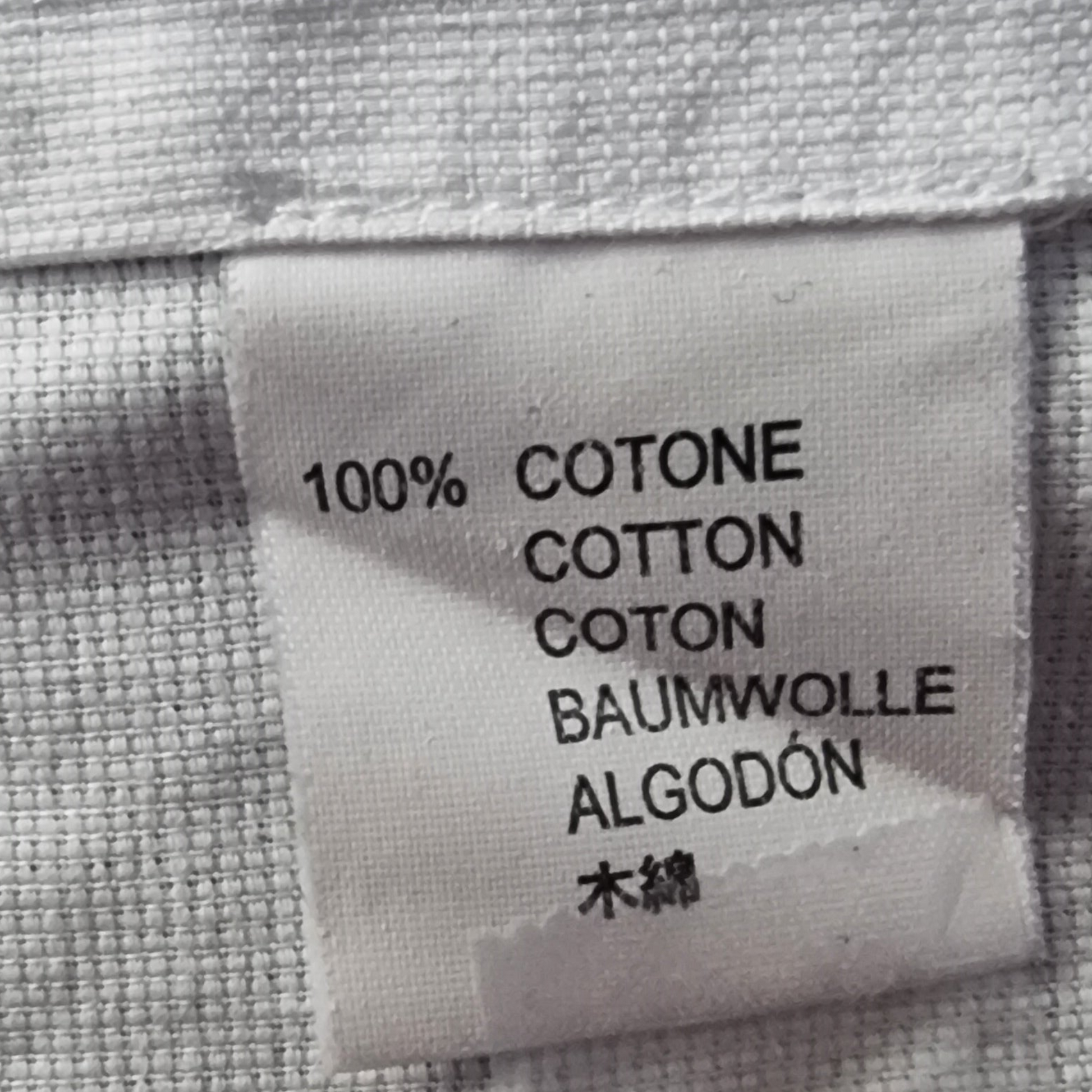 Label on fabric indicating 100% cotton in multiple languages.