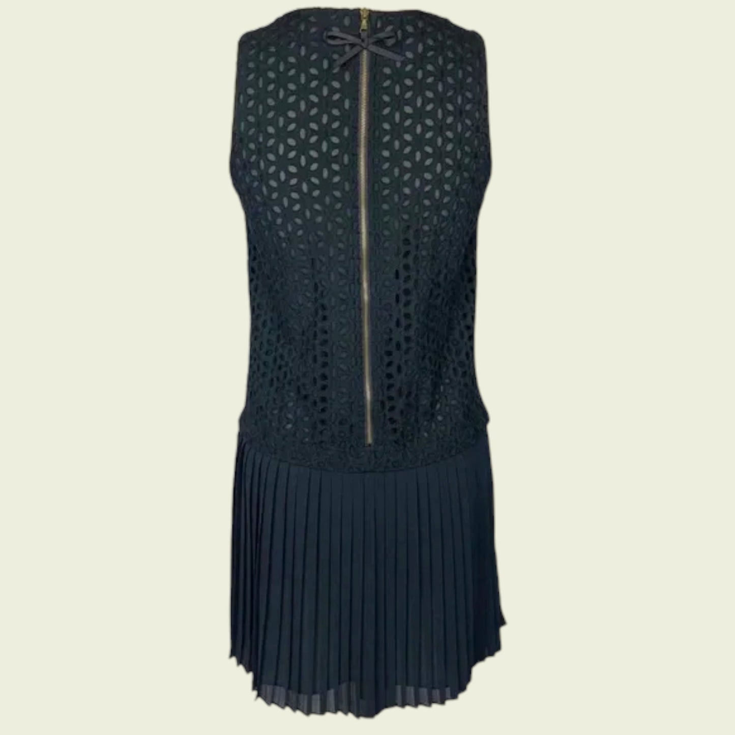 Black sleeveless dress with geometric pattern and pleated skirt on a beige background