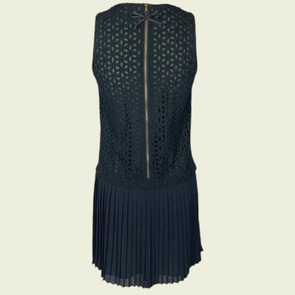 Black sleeveless dress with geometric pattern and pleated skirt on a beige background