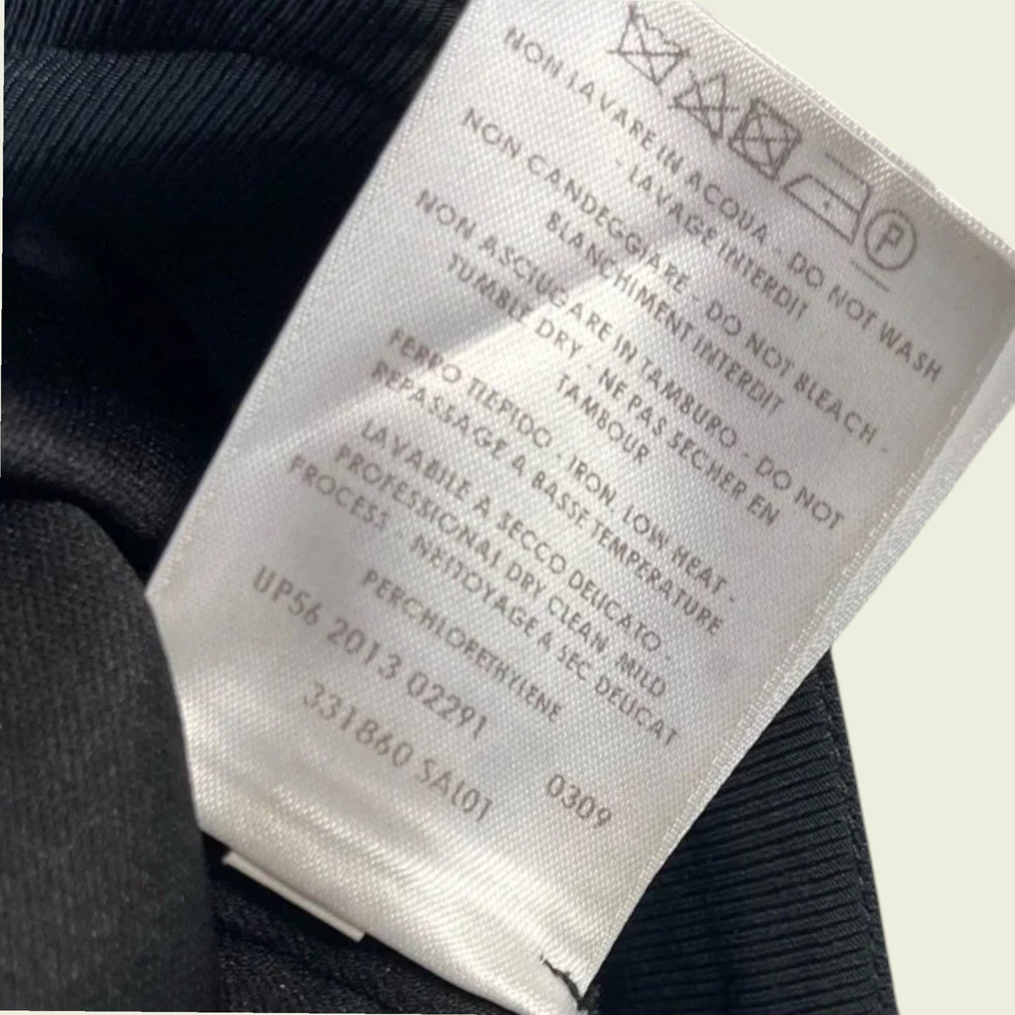 Close-up of a clothing label with text and symbols on a dark fabric background