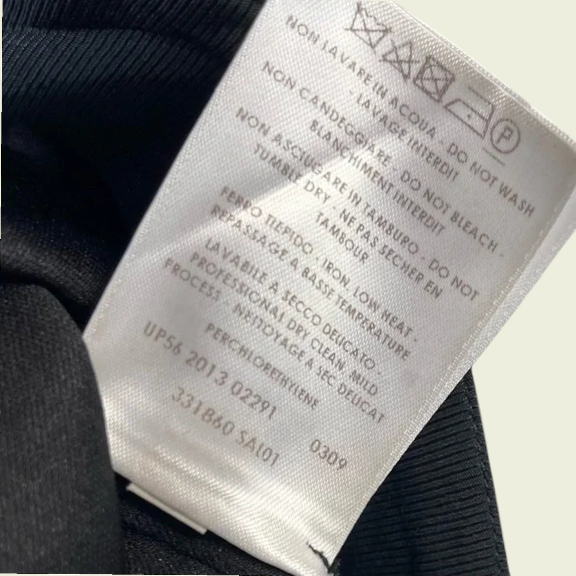 Close-up of a clothing label with text and symbols on a dark fabric background