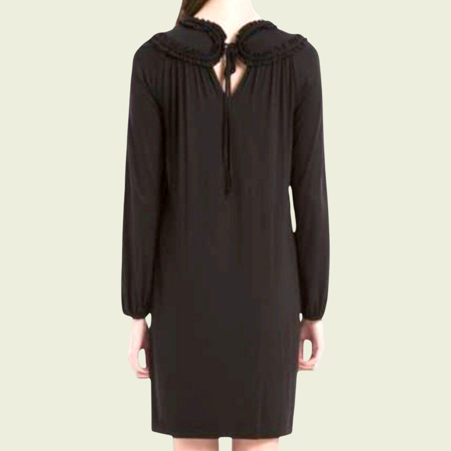 Black dress with a ruffled collar on a beige background