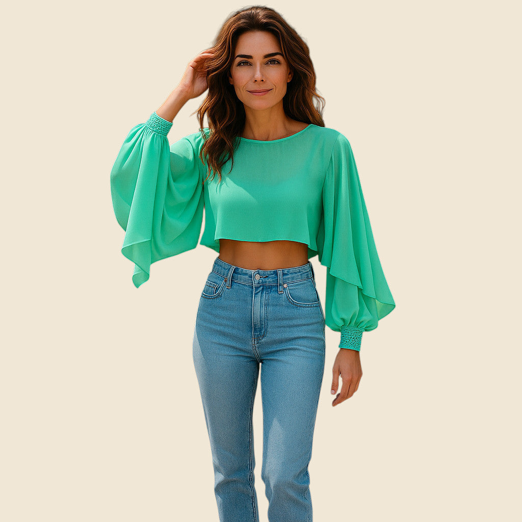 Woman wearing a green blouse with balloon sleeves and blue jeans on a beige background