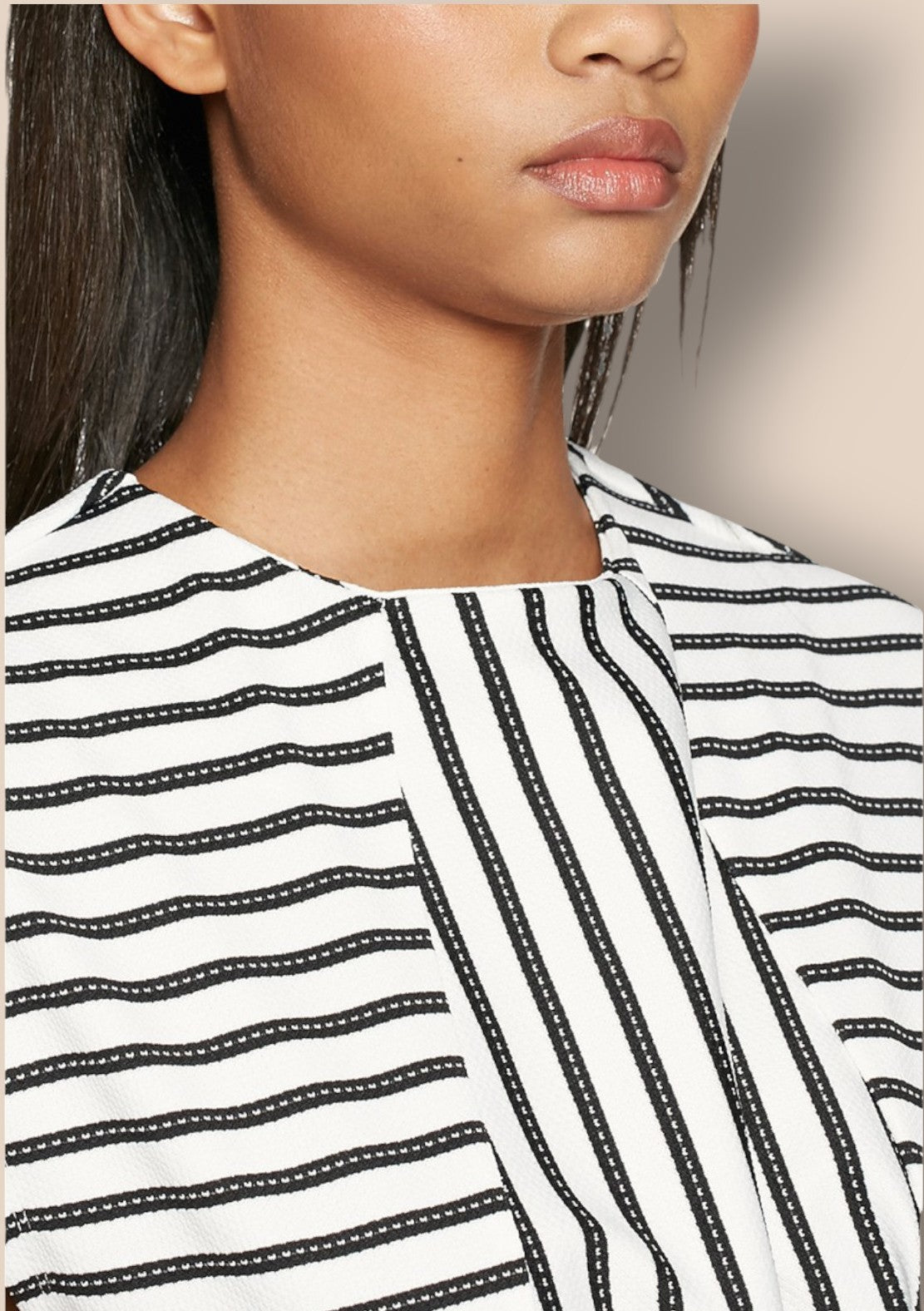 Close-up of a person wearing a black and white striped shirt with a neutral background