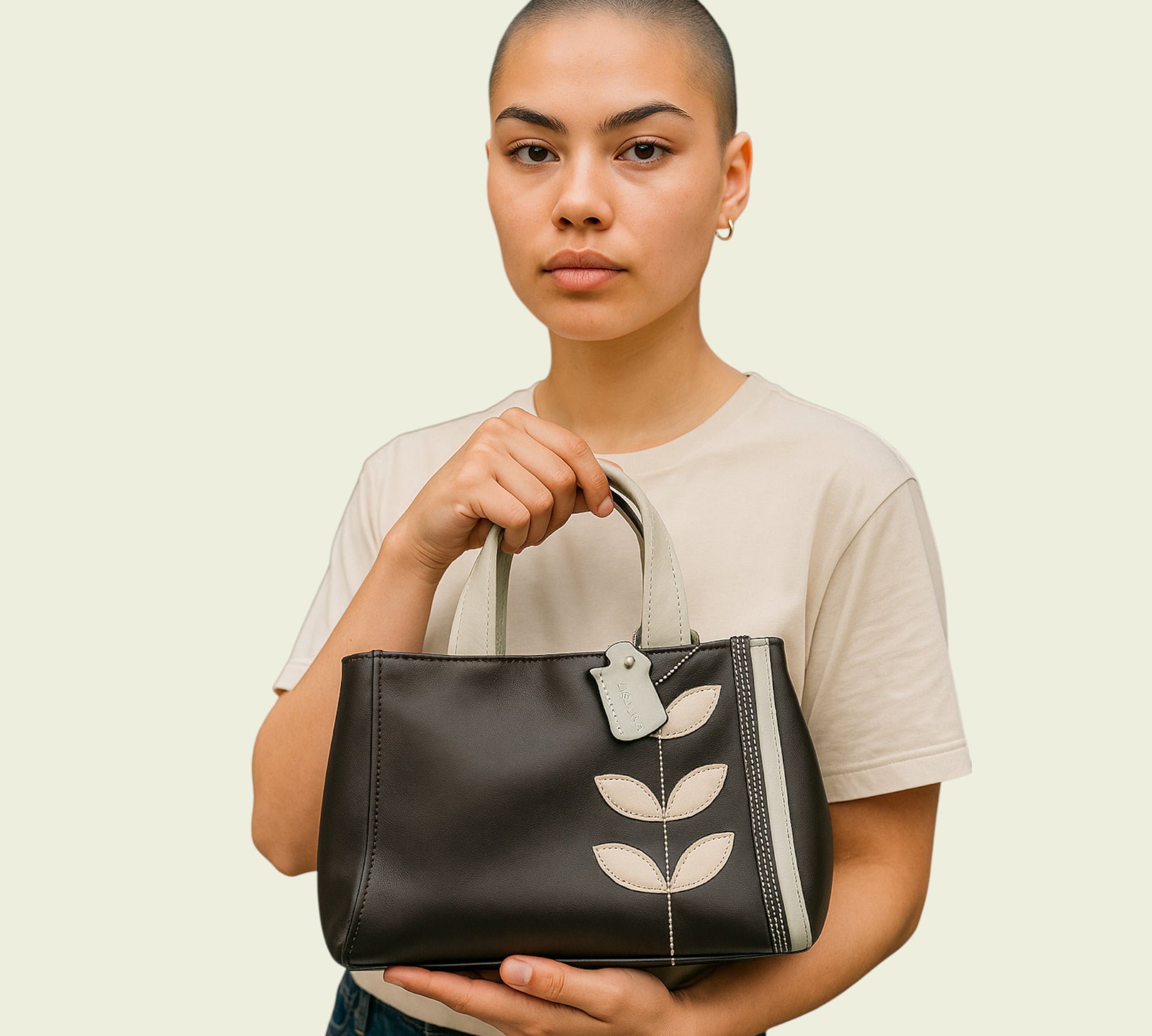 Woman holding a brown handbag with leaf designs on a beige background