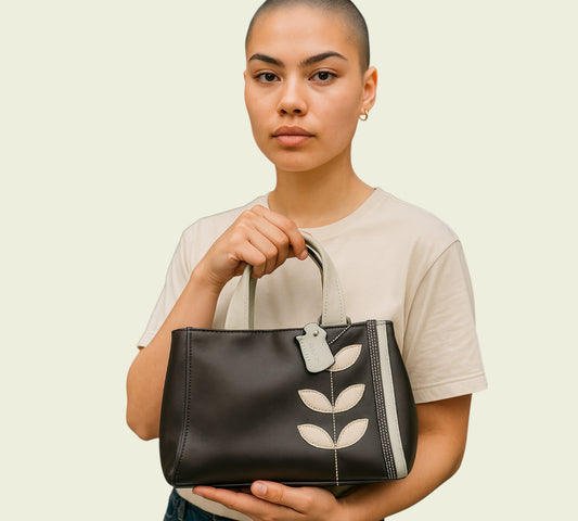 Woman holding a brown handbag with leaf designs on a beige background