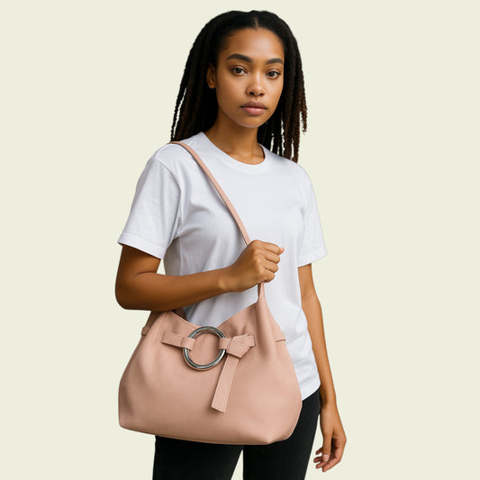 Woman holding a pink handbag with a ring detail on a beige background