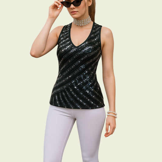 Woman wearing a black sequin tank top and white pants on a beige background