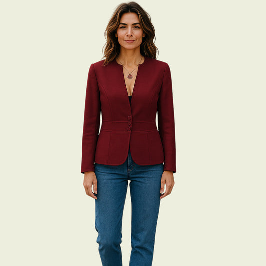 Woman wearing a burgundy blazer and blue jeans on a beige background
