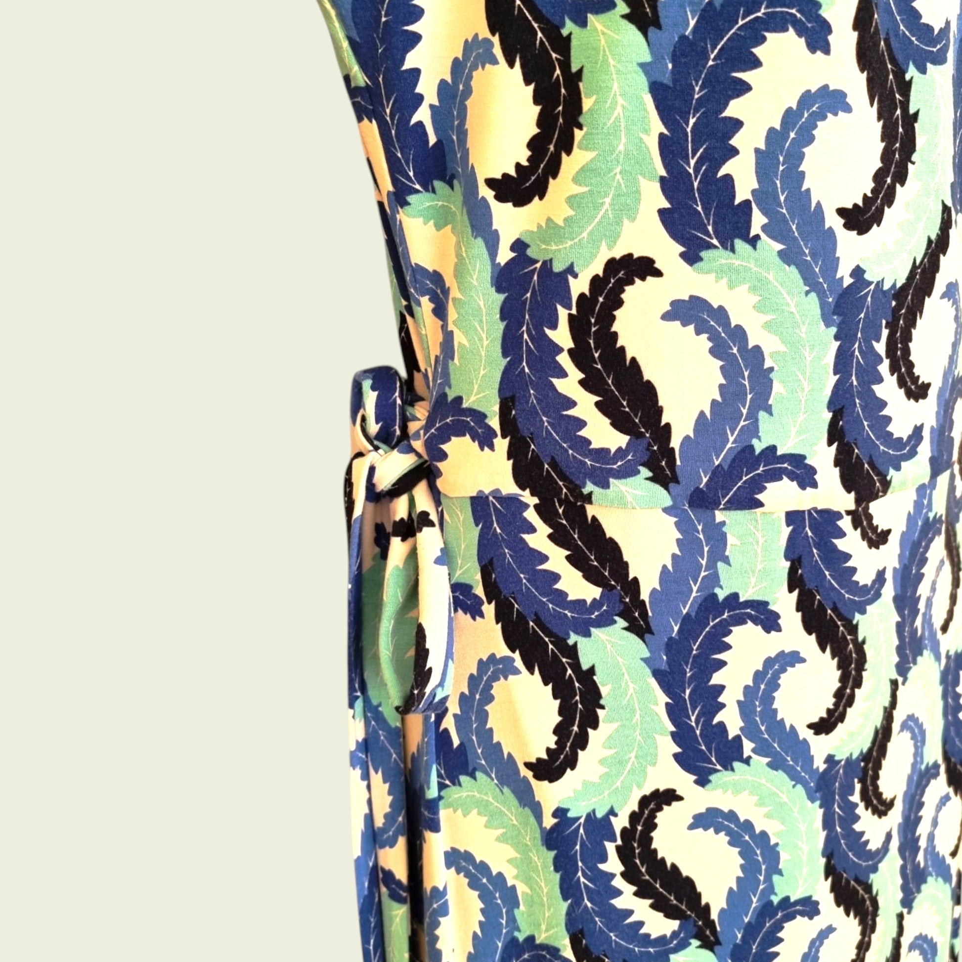 Close-up of a patterned fabric with blue, green, and black design on a beige background