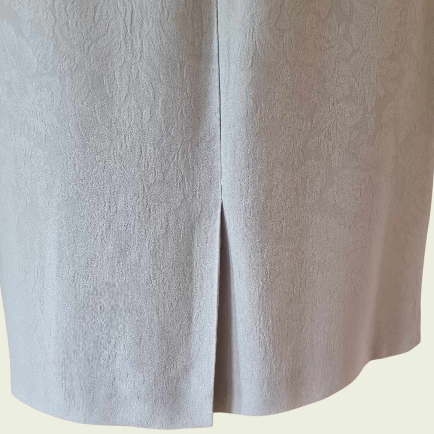 Close-up of a textured light gray skirt on a beige background