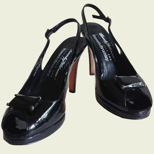 Black patent leather high-heeled shoes on a light beige background