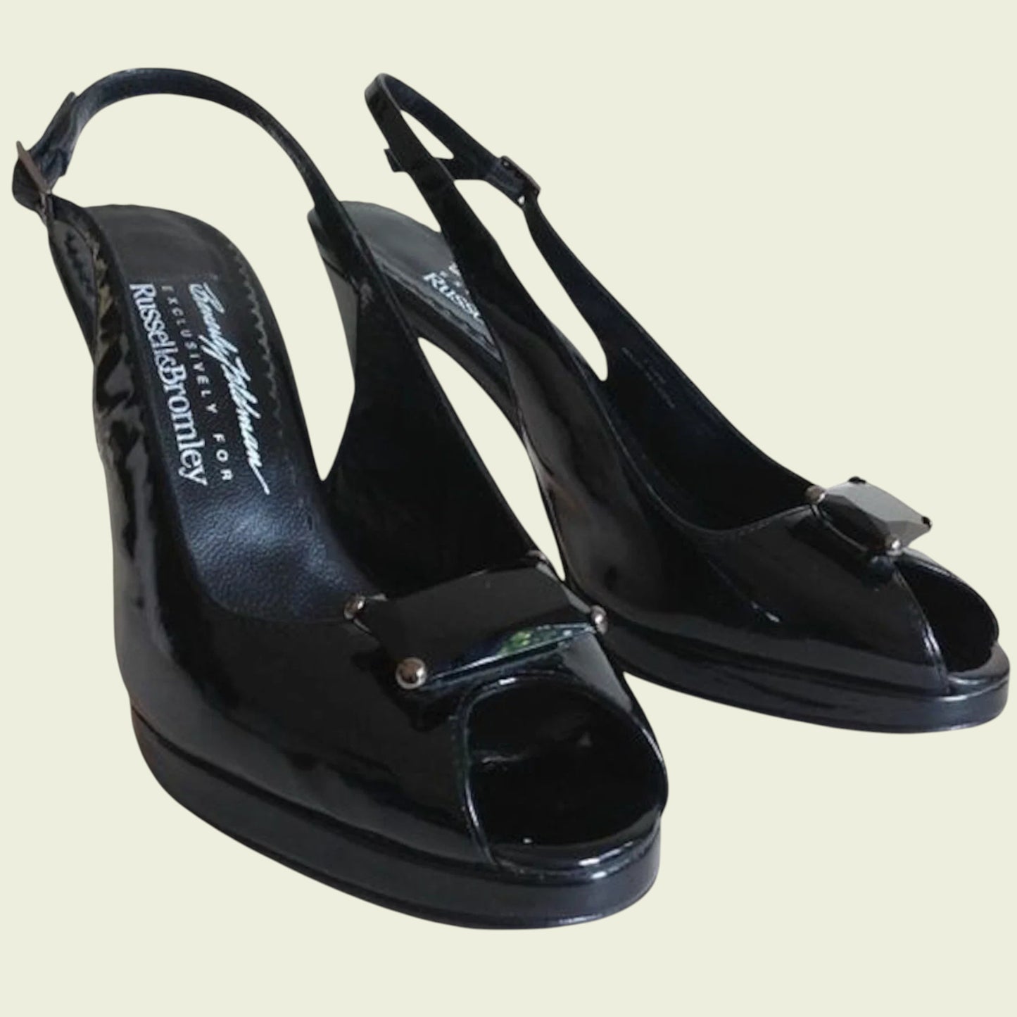 Black patent leather shoes with a bow detail on a beige background