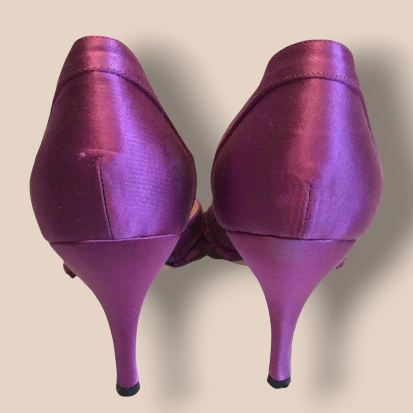 Pair of purple high-heeled shoes on a beige background